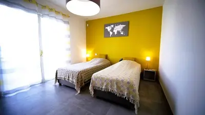 a bedroom with two beds and a yellow wall at Villa Suarticcia, 6 pers, piscine chauffée, 3 min plage en voiture in Sainte-Lucie de Porto-Vecchio