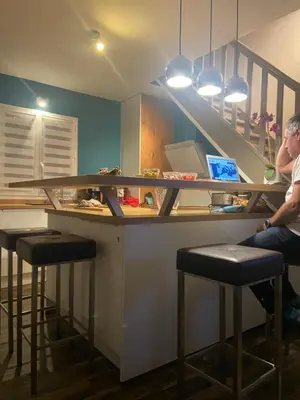 a man sitting at a bar with a counter with stools at Maison mer piscine Cargese à 1 heure d'Ajaccio in Cargèse