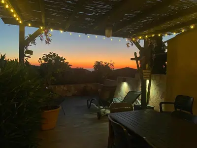 a patio with a table and chairs and a sunset at Maison mer piscine Cargese à 1 heure d'Ajaccio in Cargèse