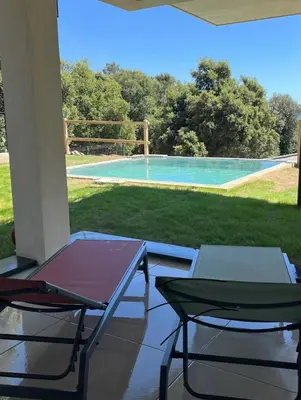 a patio with two chairs and a table and a pool at Villa vue sur le Golf 1 in Olmeto