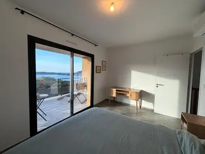 a bedroom with a bed and a desk and a balcony at Duplex Tour d'Omigna Cargèse in Cargèse
