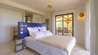 a bedroom with a large bed with a blue headboard at Villa Gaïa, 6 pers, piscine chauffée, 3 min plage in Sainte-Lucie de Porto-Vecchio