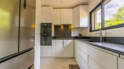 a kitchen with white cabinets and a window at Villa Gaïa, 6 pers, piscine chauffée, 3 min plage in Sainte-Lucie de Porto-Vecchio