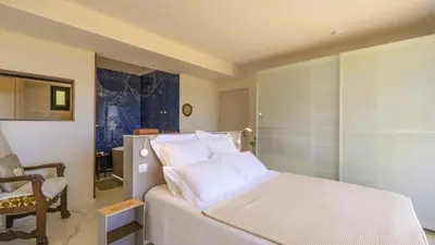 a bedroom with a white bed and a chair at Villa Gaïa, 6 pers, piscine chauffée, 3 min plage in Sainte-Lucie de Porto-Vecchio