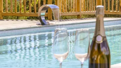 a bottle of wine and two glasses next to a swimming pool at Villa Gaïa, 6 pers, piscine chauffée, 3 min plage in Sainte-Lucie de Porto-Vecchio