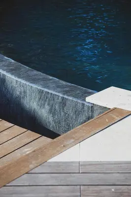a pool with a wooden deck next to the water at Villa Puccinelli in Porto-Vecchio