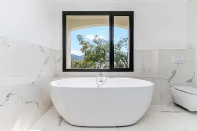 a white bathroom with a tub and a window at Villa Puccinelli in Porto-Vecchio