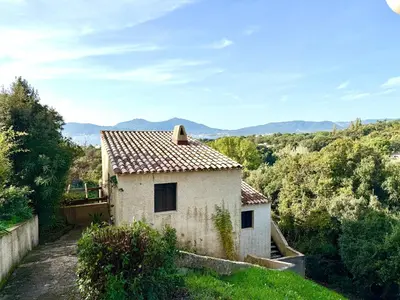 a white house with a roof with mountains in the background at Maisonnette vue mer résidence vacances Porticcio in Grosseto-Prugna