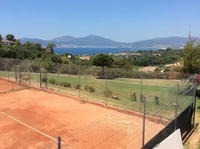 a tennis court with a net and the water at Maisonnette vue mer résidence vacances Porticcio in Grosseto-Prugna