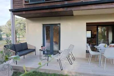 a patio with chairs and a couch and a table at Casa 115 - Plage & piscine chauffée in Pianottoli-Caldarello