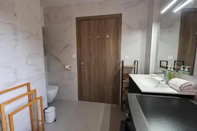 a bathroom with a sink and a wooden door at Casa 115 - Plage & piscine chauffée in Pianottoli-Caldarello