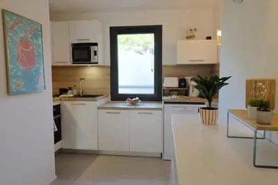 a kitchen with white cabinets and a window at Casa 115 - Plage & piscine chauffée in Pianottoli-Caldarello