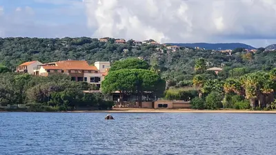 a house on the shore of a body of water at Casa 115 - Plage & piscine chauffée in Pianottoli-Caldarello
