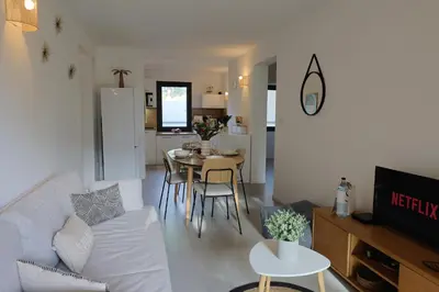 a living room with a white couch and a table at Casa 115 - Plage & piscine chauffée in Pianottoli-Caldarello