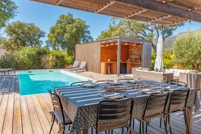 a patio with a table and chairs next to a swimming pool at A Casedda Serena Di lecci in San-Gavino-di-Carbini