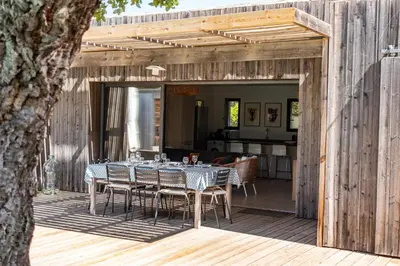 a dining table on the deck of a house at A Casedda Serena Di lecci in San-Gavino-di-Carbini