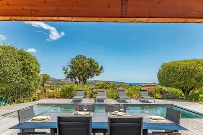 an outdoor dining area with a table and chairs and a swimming pool at Casa Di Sole Di Pinarello in Pinarellu