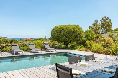 an outdoor dining area with a table and chairs next to a pool at Casa Di Sole Di Pinarello in Pinarellu