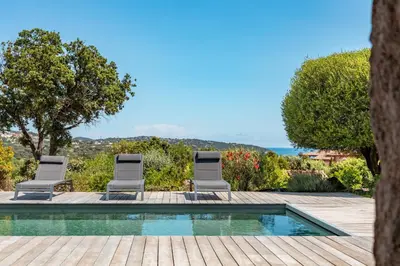 a villa with a swimming pool and two chairs at Casa Di Sole Di Pinarello in Pinarellu