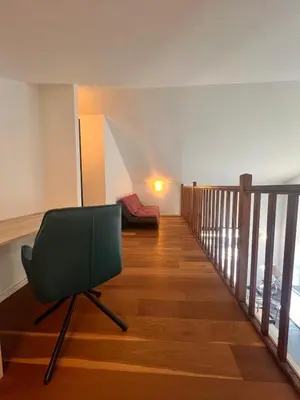 a living room with a green chair on a wooden floor at Duplex Vista in Bonifacio