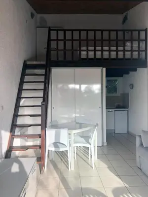 a white table and chairs in a room with a staircase at Bungalow on the sea - Moriani beach in Santa-Lucia-di-Moriani