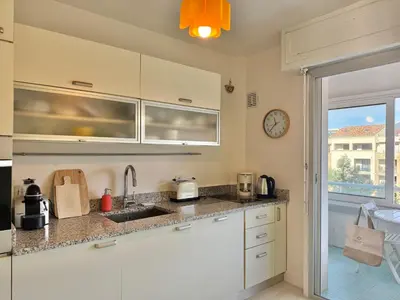 a kitchen with white cabinets and a clock on the wall at Appartement vue sur les toits de Propriano in Propriano