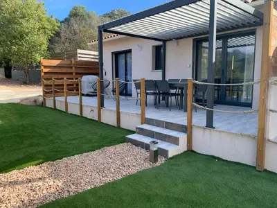 a house with a patio with a table and chairs at Villa SOLEIL in Figari