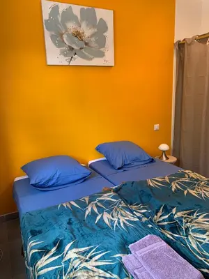 a bed with blue pillows in a room with an orange wall at Villa SOLEIL in Figari