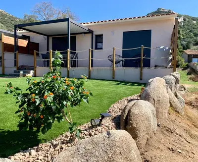 a house with a tree in a yard with rocks at Villa des Chênes in Figari