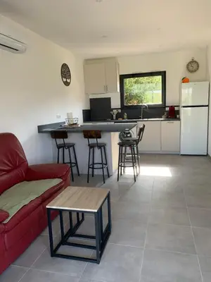 a living room with a red couch and a kitchen at Villa des Chênes in Figari