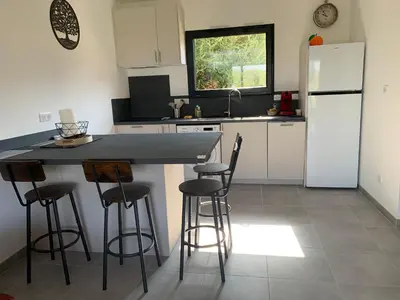 a kitchen with a counter with stools and a refrigerator at Villa des Chênes in Figari