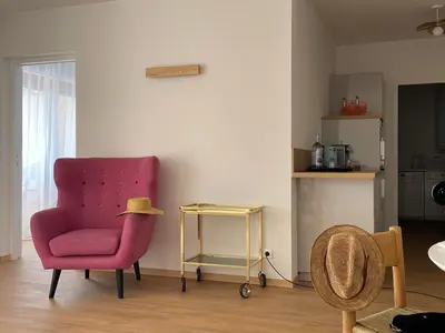 a living room with a pink chair and a table at Appartement Marinella route des Sanguinaires Corse in Ajaccio