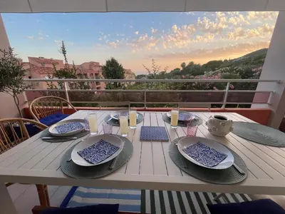 a table with plates and dishes on a balcony at Appartement Marinella route des Sanguinaires Corse in Ajaccio
