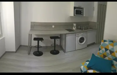 a kitchen with a counter and two stools in a room at studio centre ville in Ajaccio