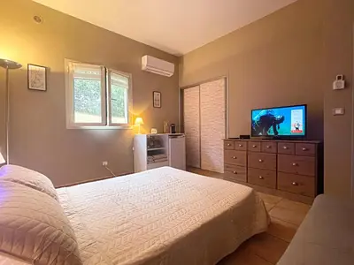 a bedroom with a white bed and a tv at Pépite du Maquis in Porto-Vecchio