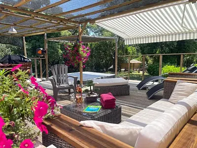 a patio with a couch and a table and some flowers at Pépite du Maquis in Porto-Vecchio