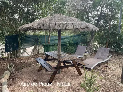 a picnic table and two chairs under an umbrella at Pépite du Maquis in Porto-Vecchio