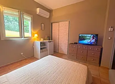 a bedroom with a bed and a television on a dresser at Pépite du Maquis in Porto-Vecchio