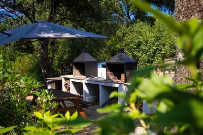 a picnic table with a blue umbrella and a table with chairs at Domaine de la Testa in Sainte-Lucie de Porto-Vecchio