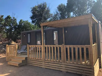 a cabin with a wooden deck and a chair at Domaine de la Testa in Sainte-Lucie de Porto-Vecchio