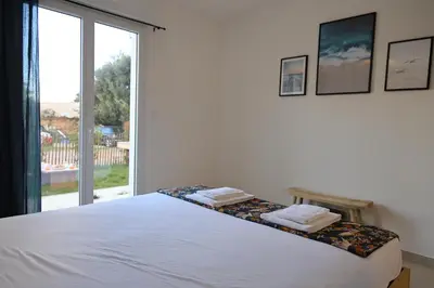 a bedroom with a white bed with a large window at I Tramizzi - Maison 3 Chambres à Bonifacio in Bonifacio