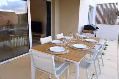 a wooden table with chairs and plates and wine glasses at I Tramizzi - Maison 3 Chambres à Bonifacio in Bonifacio