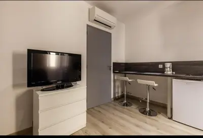 a living room with a flat screen tv and a counter at joli studio centre ville in Ajaccio