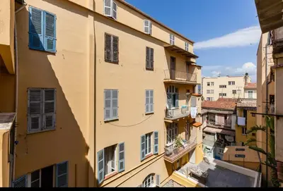 a tall yellow building with blue shuttered windows at joli studio centre ville in Ajaccio