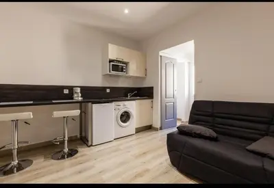 a living room with a couch and a kitchen at joli studio centre ville in Ajaccio