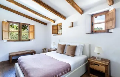a white bedroom with a bed and two windows at U Caseddu in Sotta