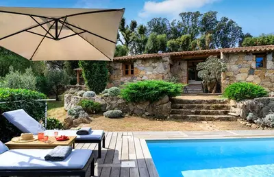 a patio with an umbrella and a swimming pool at U Caseddu in Sotta