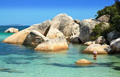 a person standing in the water near some rocks at U Caseddu in Sotta