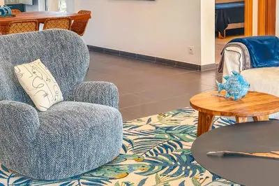 a living room with a blue chair and a table at Villa Mathilda Di Porto-Vecchio in Lecci