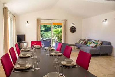 a dining room with a table and red chairs at Villa Capanaccia Di Arasu in Sainte-Lucie de Porto-Vecchio
